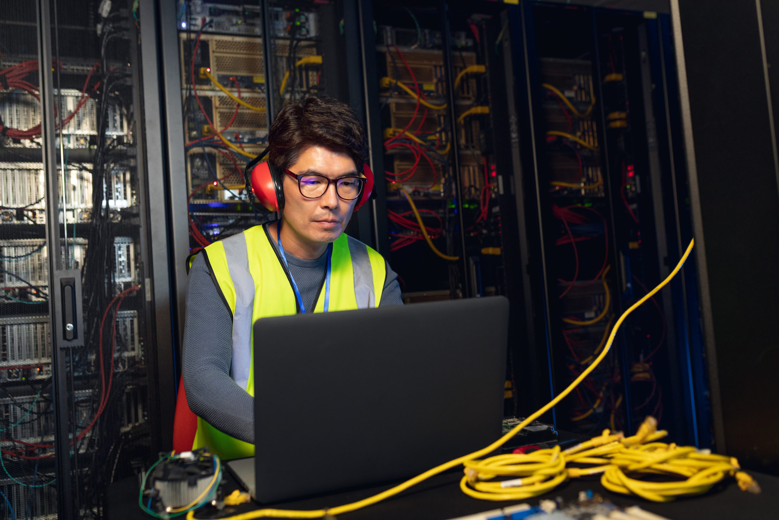 Engineer wearing ear plugs using a laptop